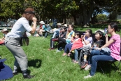 Thumper (Joan Howard) rallies a kazoo band at a performance of Shakespeare or Space Wars in San Antonio Park, Oakland. Photo by Serena Morelli